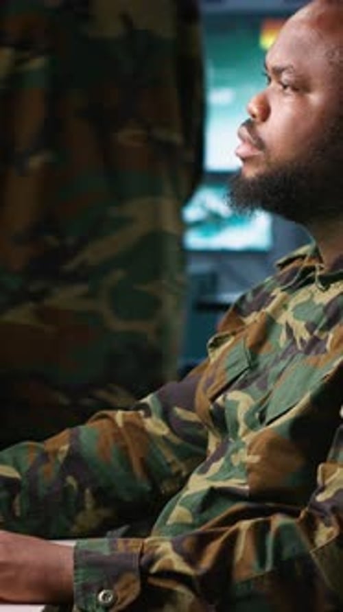 Man in Camouflage Using Telephone in Control Room