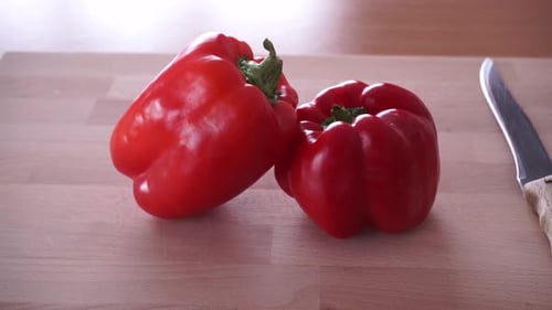 Two Red Bell Peppers with Knife on Cutting Board