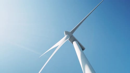 Large wind turbine in field against blue sky on sunny summer day slow motion