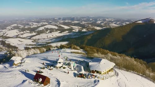 Old Ski Station on a Snowy Mountain Slope with a Lot of People on Skis and Snowboards