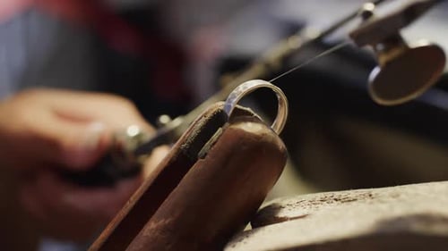 Biracial female worker shaping jewellery with saw in studio in slow motion