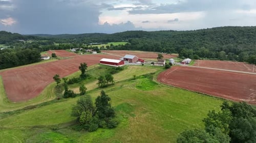 Annäherungsaufnahme einer amerikanischen Farm in ländlicher Gegend mit Scheunengebäude aus rotem Backstein im Sommer.
Groß