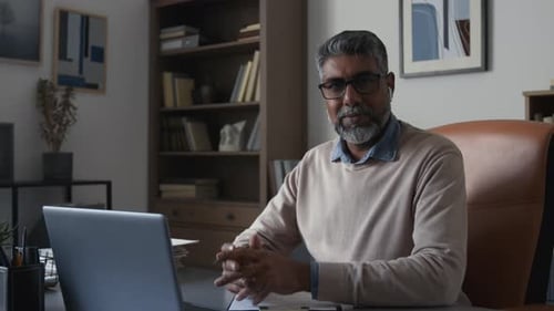 Man with Gray Hair at Desk Working with Laptop