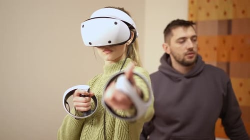 Woman Uses Virtual Reality Headset With Man Watching
