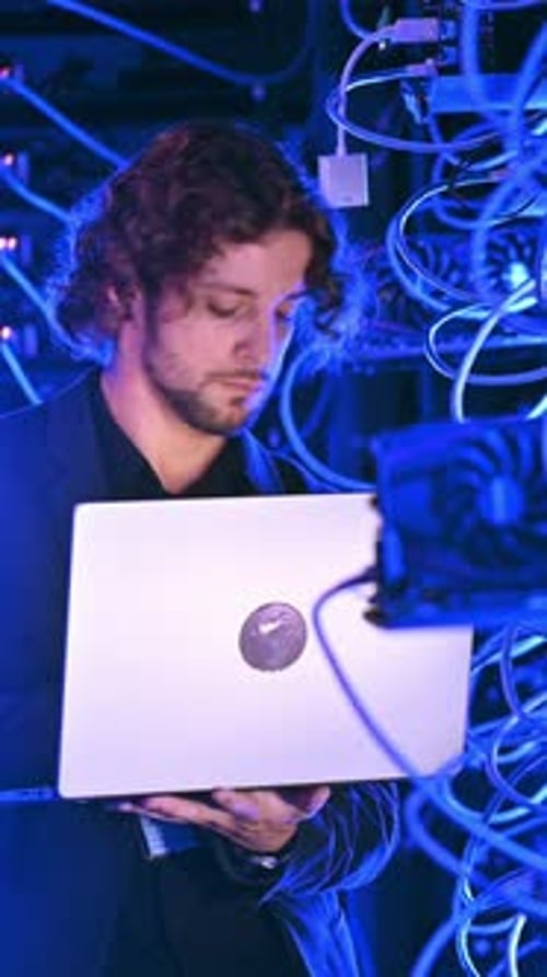 Young Adult Working on Laptop in Server Room