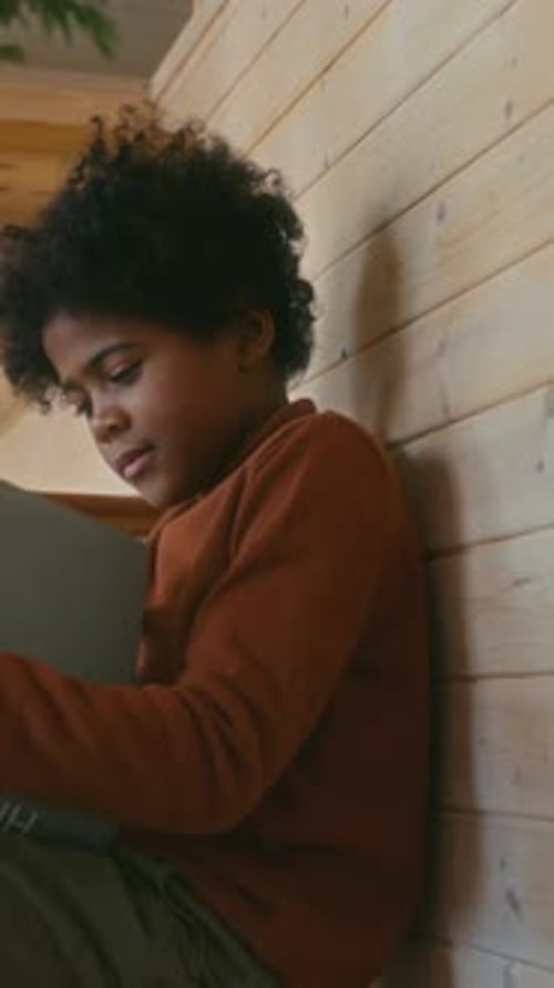 Boy Holds History Book Sitting Inside by Stairs