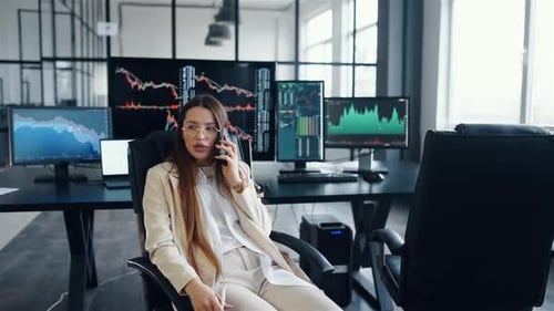 Une femme excitée parle au téléphone. Une équipe de courtiers en valeurs mobilières travaille ensemble dans des bureaux modernes pendant la journée