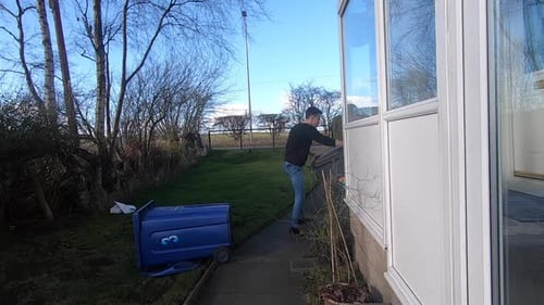 Caucasian man picking up rubbish bins that have fallen over