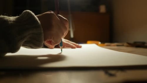 Creative crisis, hand holding colored pencil over blank paper, close up