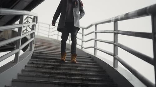 Man Walks Down Urban Staircase in Stylish Outerwear