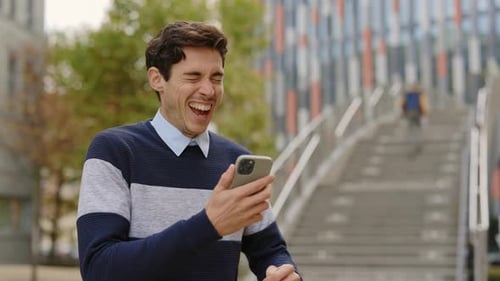 Excited Man Celebrates Good News on Phone Outdoors