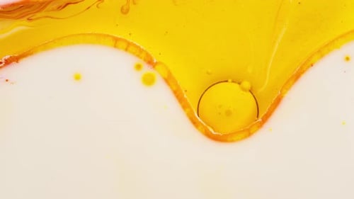 Yellow acrylic paint spreading in white liquid