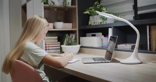 Child Studying at Desk with Laptop and Lamp