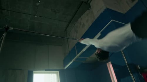 Young Man Doing Tricks on Gymnastics Bar