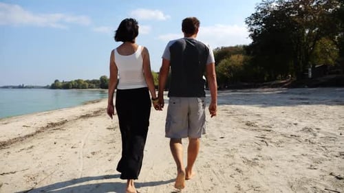 Couple Holding Hands Walking on a Sunny Beach