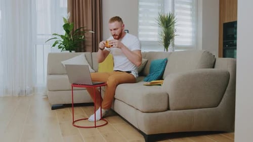 Man With Reddish Hair Works on Laptop at Home