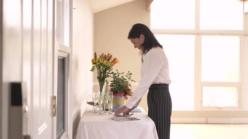 Woman Arranging Table with Champagne and Flowers