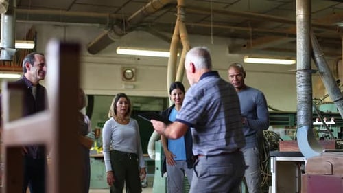 Workers Gather Around Supervisor in Woodworking Shop