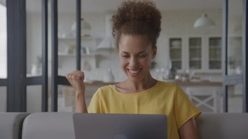 Close Up of an African American Woman Receiving Good New and Celebrate an Achievement on Her Laptop