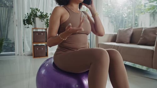 Woman Talking on Phone While Exercising on Ball