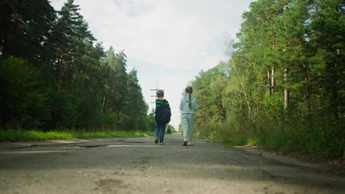 Rear View of Children Walking Toward Power Lines on Forest Road