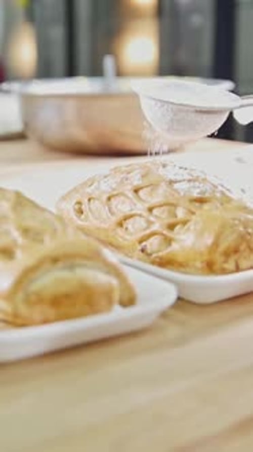 Freshly Baked Pastries Being Plated with Sugar on a Wooden