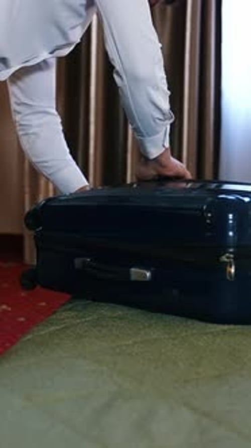 Businessman packing luggage in hotel room.