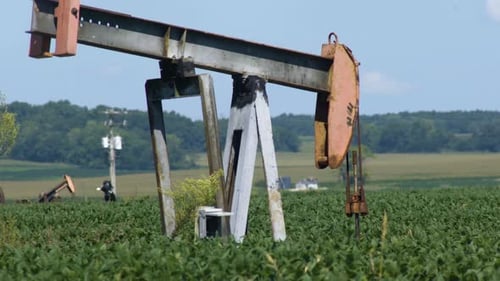 An old Oiljack continues with an almost perpetual motion to pump oil on a farm in Midwest America.