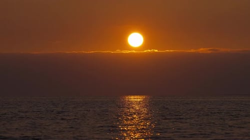 Sun up in the sky during the sunset with ocean seascape view illuminated with golden hour