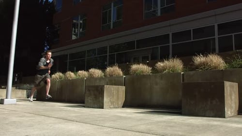 Athletic Young Man Performing Parkour Jumping Obstacles