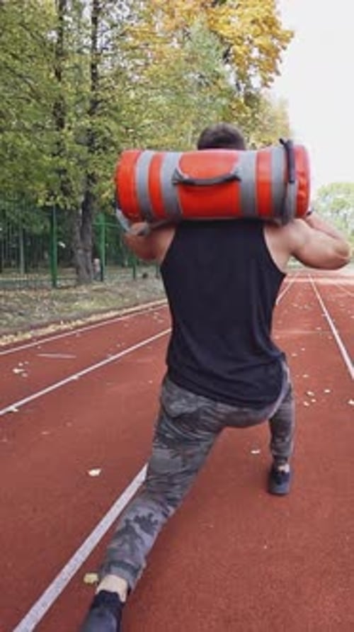 Young man exercising outdoors. Muscular built young athlete working out on stadium
