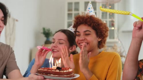 Friends Celebrate Birthday with Cake and Party Blowers