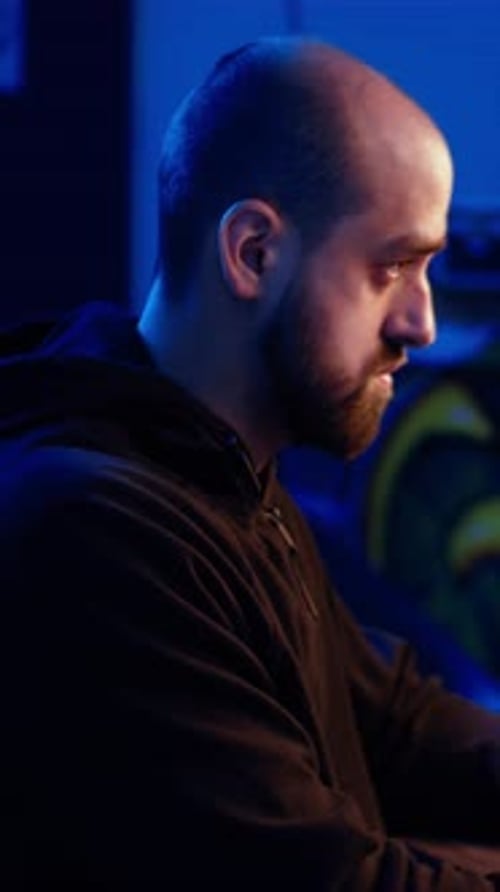 Man Typing on Computer in Dark Blue Room