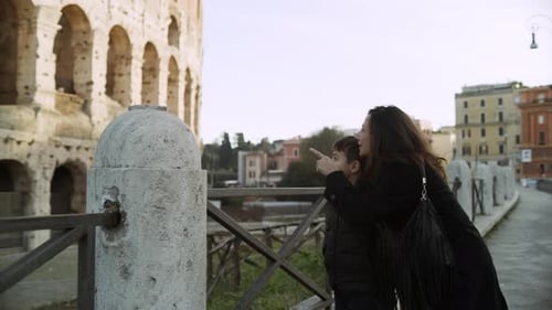 Excited italian mother and son explore the majestic coliseum in Rome Italy