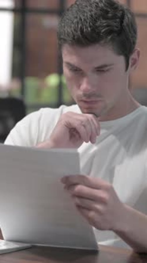 Man Reviews Documents at Office Desk