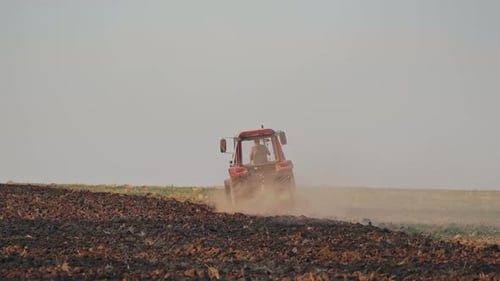 Tractor working on large field. Farmer in tractor preparing land with seedbed cultivator