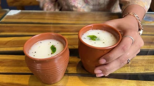 Two glasses of butter milk with mustard seed served in a restaurant in India.