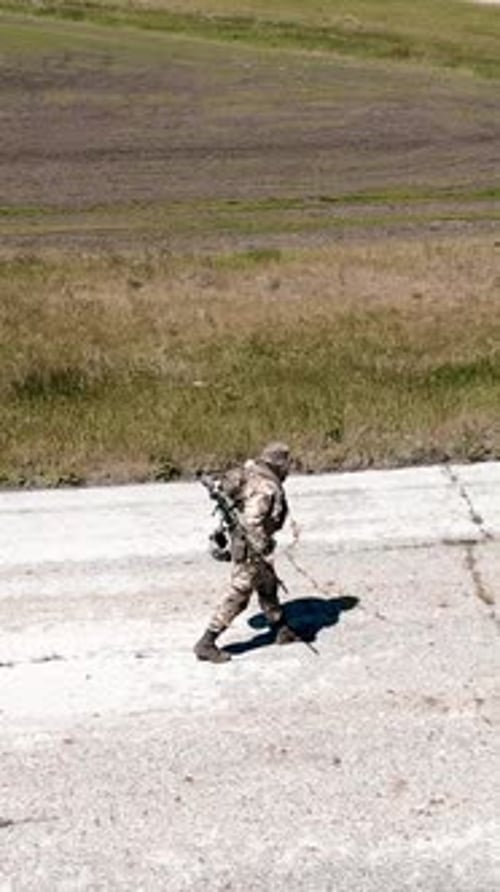 Aerial View of a Lonely Soldier Walks Along an Old Concrete Road