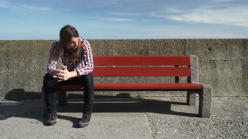 Man Sits Alone on Bench in Urban Setting