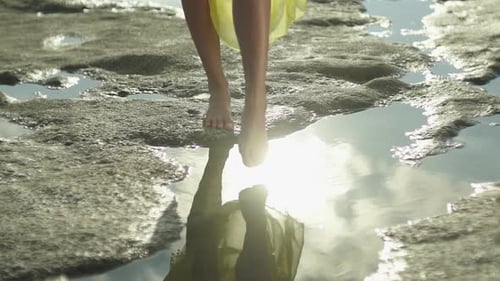 young girl immerses her toe in water in the rock near the sea.