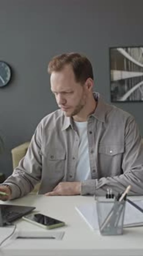 Young Man Using Laptop at Workplace in Office