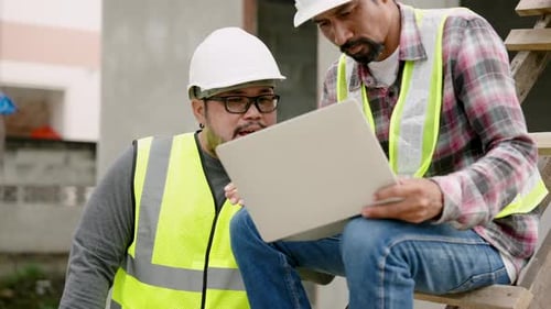 Male asia engineers sitting with laptop computers on their legs, working on computer, another builde