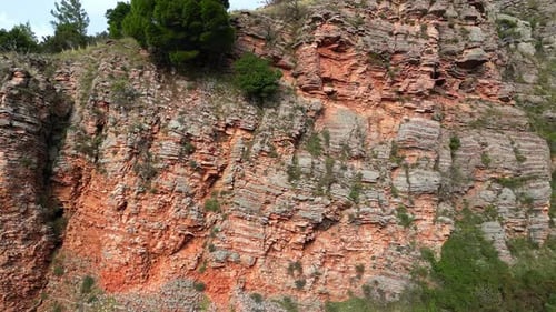 The Drone Approaches a Red Layered Relief Rock