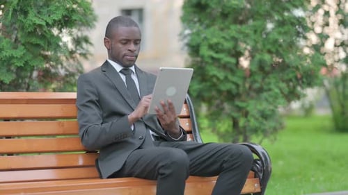 Man Working on Tablet Device in Park