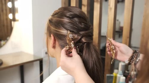 Hairdresser Attaches Stylish Hair Accessories on a Client While Making Her a Wedding Hairstyle