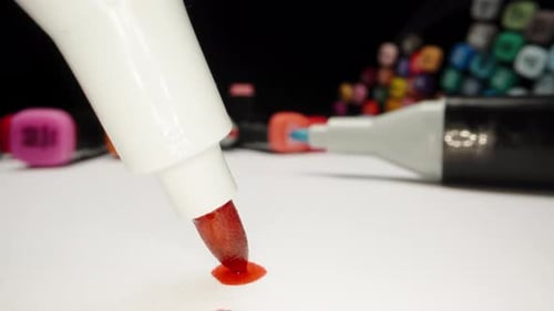 Mehrfarbige Markierungen auf dem Tisch. Die rote Markierung berührt das Papier und hinterlässt einen großen Fleck. extr