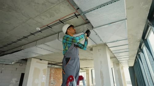 Construction Worker Installing Air Duct Insulation in Building