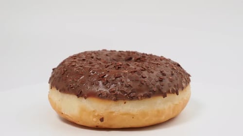 Rotating chocolate donut with chocolate chips on a white background.
