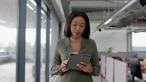 African american businesswoman using digital tablet while walking in office