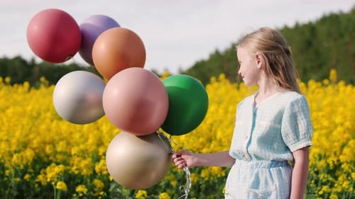Pretty Girl Standing Among Yellow Meadow with Air Balloons